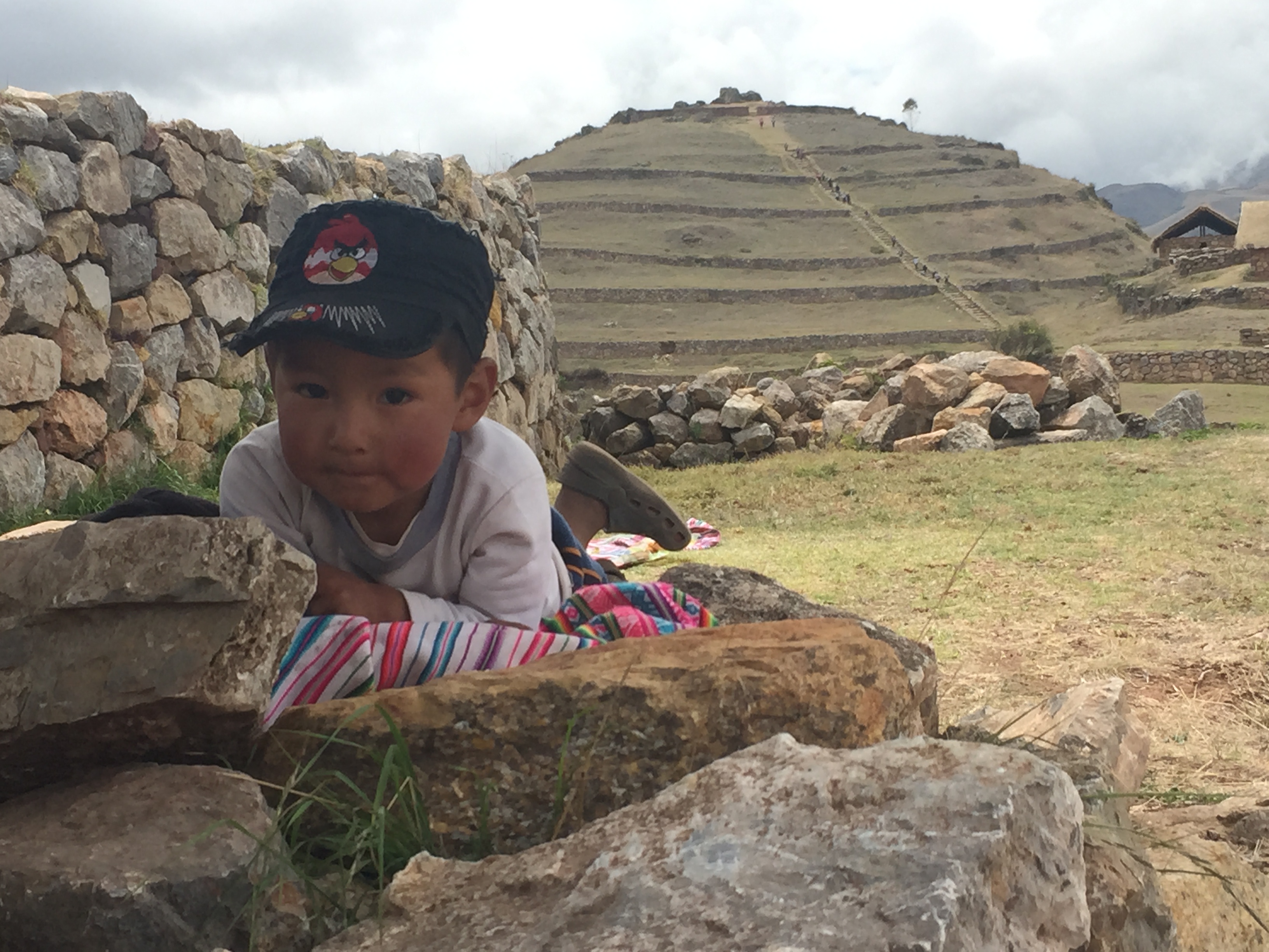 Niño de comunidad andina frente a terrazas incas — Perú
